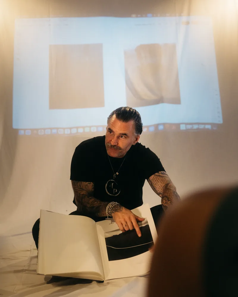 Matt walks the group through a photobook, projected work behind him